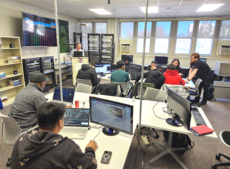 a cyber games competition with professor at podium and active club member students
